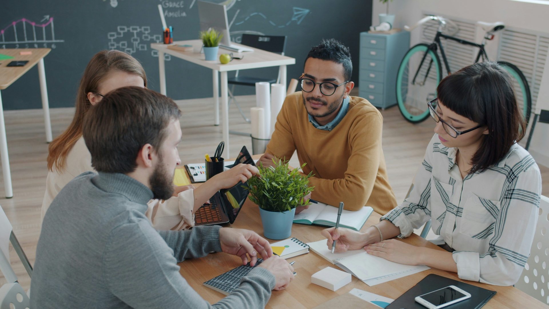 Ein diverses Team arbeitet gemeinsam an einem Tisch im Büro.